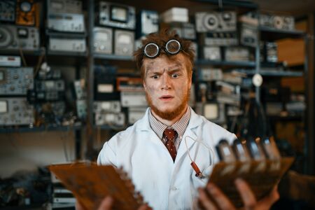 Strange engineer looks on electronic chips in lab