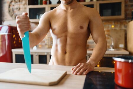 Man with naked body cooking on the kitchenの写真素材