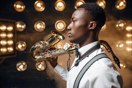 Black jazz performer poses with saxophone on stageの写真素材