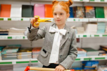 Schoolgirl choosing scissors in stationery store