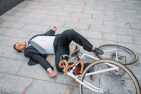 Businessman fell off bicycle near office buildingの写真素材