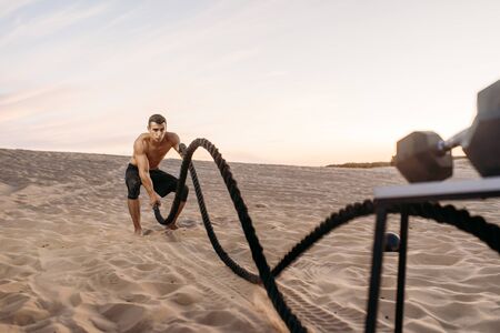 Athlete doing exercise with battle ropes in desertの写真素材