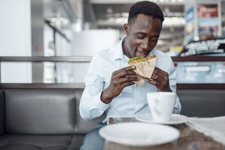 Negro businessman eating sandwich in car showroomの写真素材