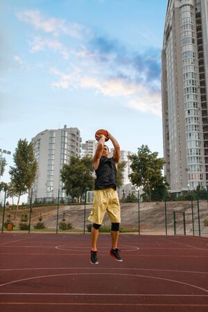 Basketball player makes a throw on outdoor court