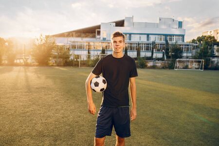 Male soccer player poses with ball in handsの写真素材