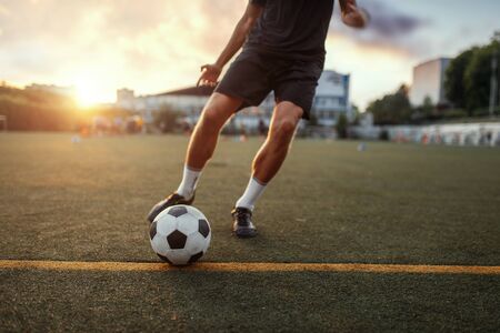 Male football player hits the ball on the field. Footballer on outdoor stadium, workout before competition, soccer trainingの写真素材