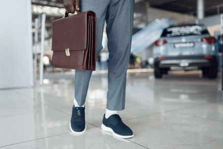 Businessman holds briefcase in car showroomの写真素材