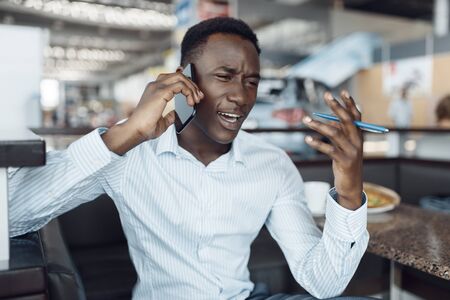 Negro businessman talking by phone, car showroomの写真素材