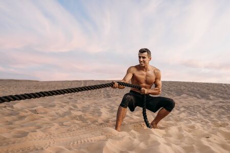 Athlete doing exercise with battle ropes in desertの写真素材