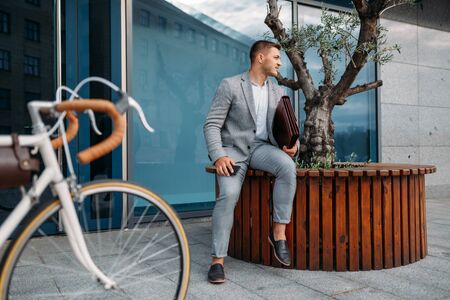 Businessman bicyclist puts document into briefcaseの写真素材
