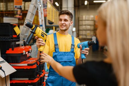 Consultant and female buyer in hardware store. Seller in uniform and woman in diy shop, chipboard...