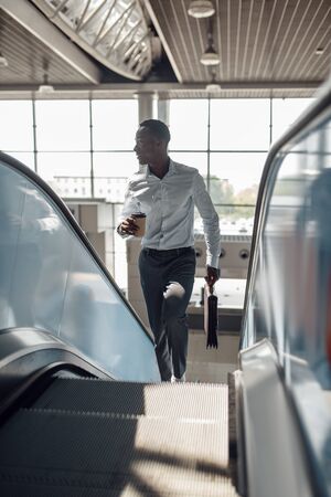 Businessman talking by phone on escalator in mallの写真素材