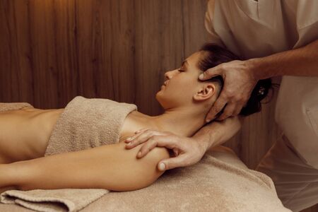 Male masseur rubbing neck vertebrae to young womanの写真素材