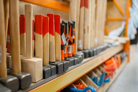 Hardware store assortment, shelf with hammers, nobody. Building materials and tools choice in diy shop, rows of products on racksの写真素材