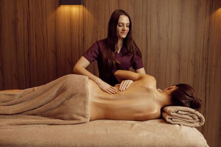 Female masseur pampering ribs to young slim womanの写真素材