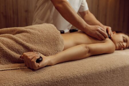Male masseur puts stones on back of slim womanの写真素材