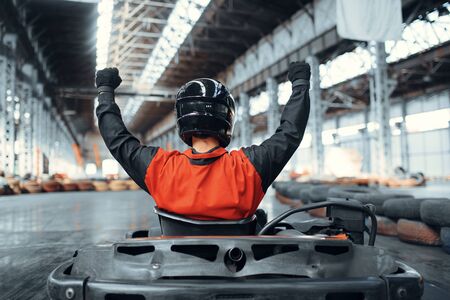 Go kart racer raised his hands up, winner, back view, karting auto sport indoor. Speed race on close...