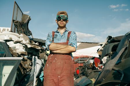 Dirty repairman in welding glasses on car junkyardの写真素材