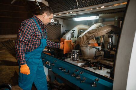 Carpenter in uniform near woodworking machine
