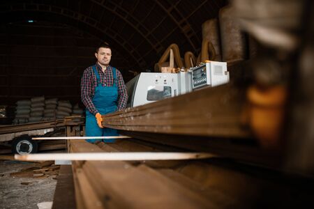 Carpenters in uniform holds stack of boards