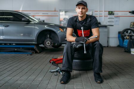 Auto mechanic sitting on wheels, tire serviceの写真素材