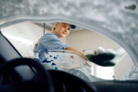 Woman wipes windshield, view from interior