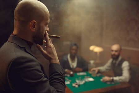 Three poker players sitting at the table in casino. Games of chance addiction, gambling house,