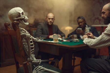 Poker players and skeleton at gaming table, fun