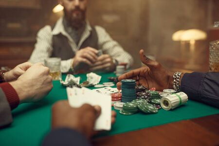 Male poker players at gaming table with green cloth, casino. Games of chance addiction, risk, gambling house. Men leisures with whiskey and cigarsの写真素材