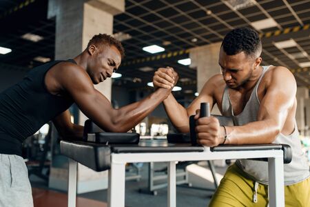 Two men fighting, arm wrestling training in gymの写真素材