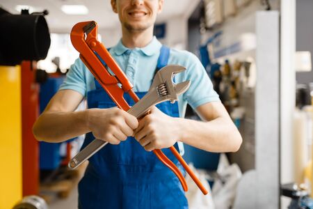 Plumber poses with pipe wrenches, plumbering storeの写真素材