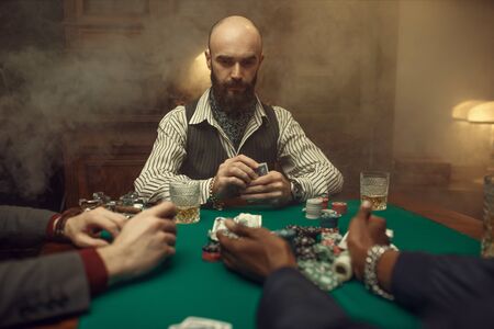 Poker players with cards and chips in casino