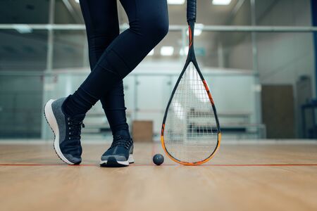 Female player legs, squash racket and ball