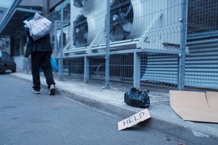 Homeless man and help sign on city streetの写真素材