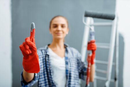Young woman shows glove in paint, home repairの写真素材