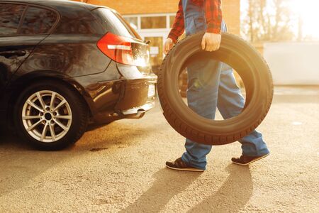 Male worker in uniform holds tyre, tire serviceの写真素材