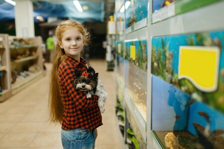 Girl looking on fishes in aquarium, pet storeの写真素材
