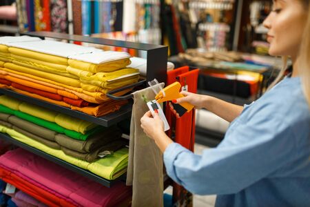 Female seller holds fabric in textile storeの写真素材
