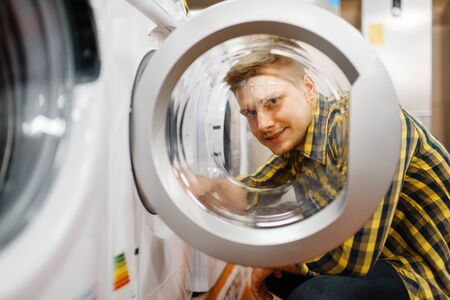 Man choosing washing machine in electronics store
