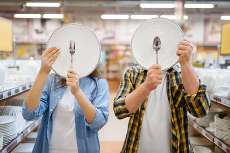 Couple jokes with plates in houseware store