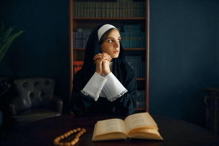 Young nun in a cassock prays crossed her armsの写真素材