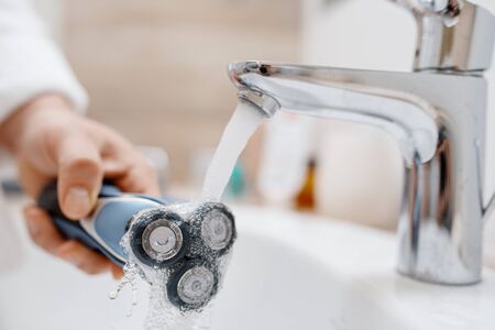 Man cleans electric razor after shavingの写真素材
