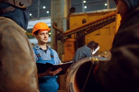 Master and crew of welders works on factory