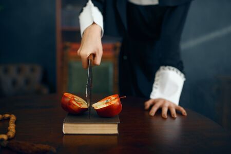 Nun in a cassock cuts the apple of discordの写真素材