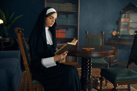 Young nun in a cassock reads a prayerの写真素材