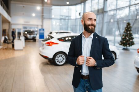 Smiling man poses in car dealershipの写真素材