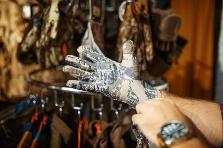 Man choosing gloves for hunters in gun shopの写真素材