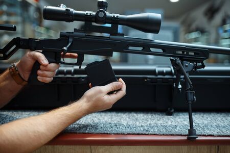 Male person loads sniper rifle in gun shop