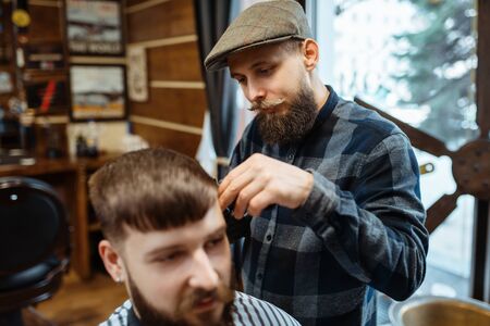 Barber holds comb and cuts the client s hairの写真素材