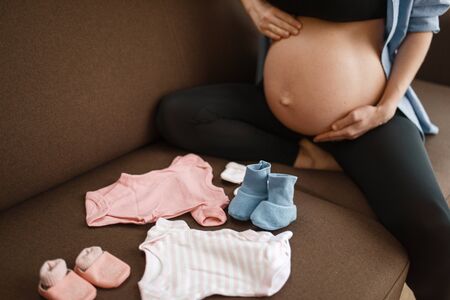 Pregnant woman prepares clothing for newborns
